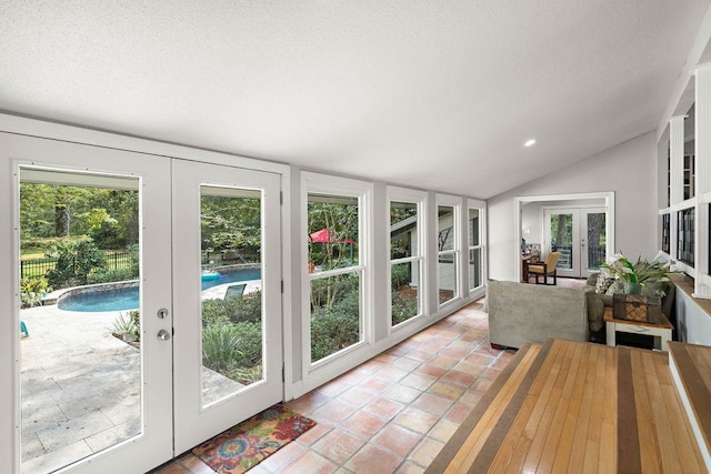 sunroom featuring lofted ceiling, french doors, and a healthy amount of sunlight