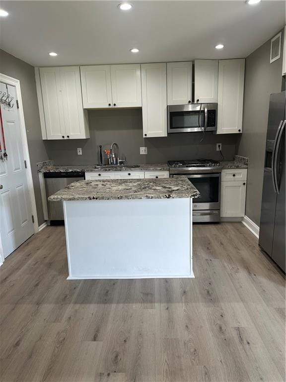 kitchen featuring light stone countertops, stainless steel appliances, white cabinetry, and sink