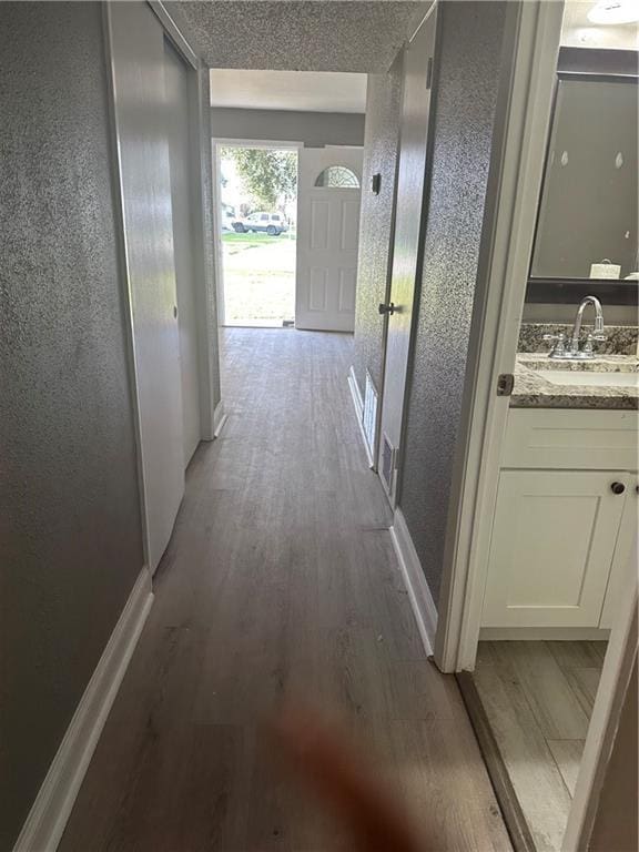 hallway with a textured ceiling, dark hardwood / wood-style floors, and sink