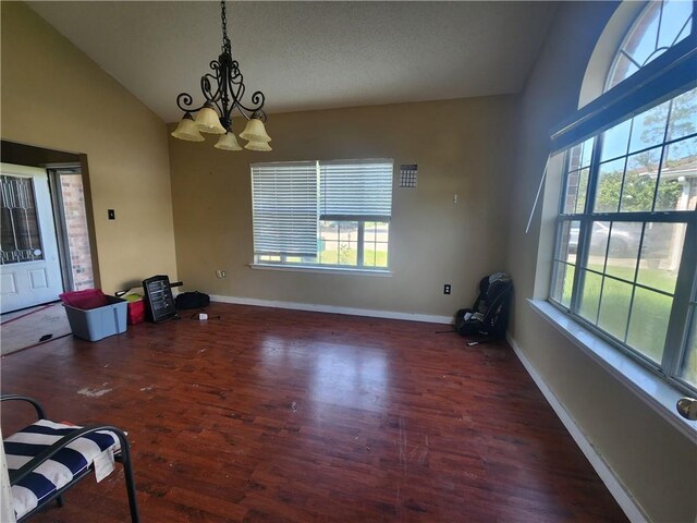 unfurnished dining area with a textured ceiling, a notable chandelier, vaulted ceiling, and dark hardwood / wood-style flooring