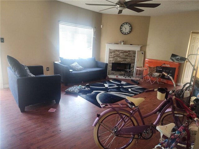 living room featuring a fireplace, ceiling fan, and wood-type flooring