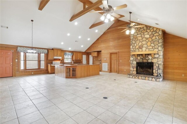 unfurnished living room featuring high vaulted ceiling, a fireplace, wooden walls, and light tile patterned floors