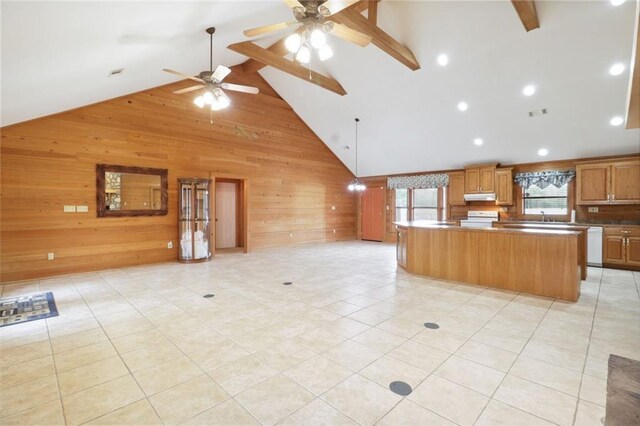 kitchen featuring light tile patterned floors, a center island, high vaulted ceiling, wood walls, and ceiling fan