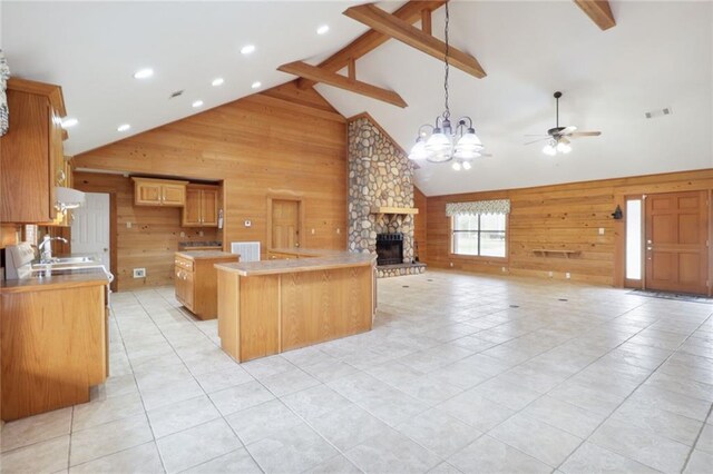 kitchen featuring wooden walls, extractor fan, a fireplace, a center island, and high vaulted ceiling