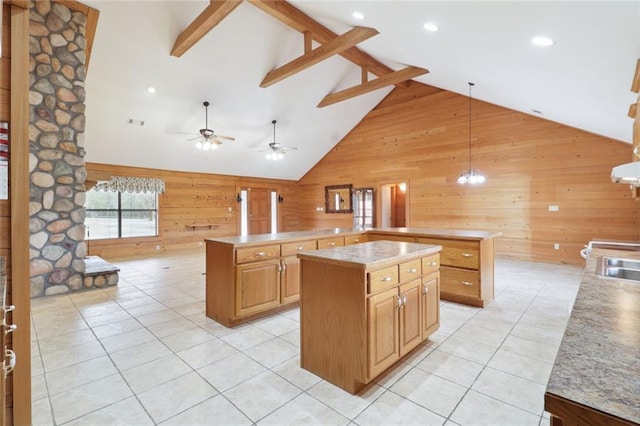 kitchen featuring beam ceiling, wooden walls, a kitchen island, ceiling fan, and high vaulted ceiling