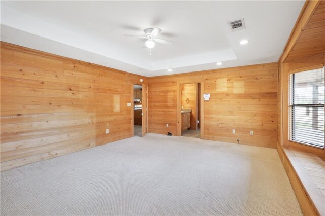 unfurnished room with wooden walls, light carpet, and ceiling fan