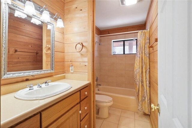 full bathroom featuring wooden walls, shower / bath combo with shower curtain, toilet, tile patterned floors, and vanity