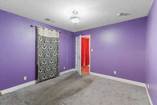 carpeted empty room with a textured ceiling