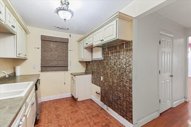 kitchen featuring stainless steel dishwasher, white cabinetry, backsplash, dark tile floors, and sink