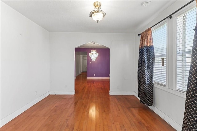 unfurnished room featuring an inviting chandelier and dark hardwood / wood-style flooring