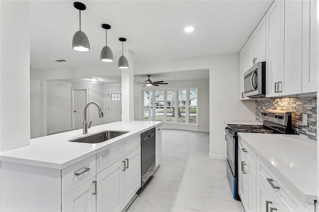 kitchen featuring appliances with stainless steel finishes, white cabinetry, and an island with sink