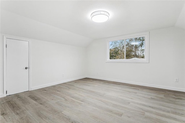 additional living space with light hardwood / wood-style flooring and vaulted ceiling