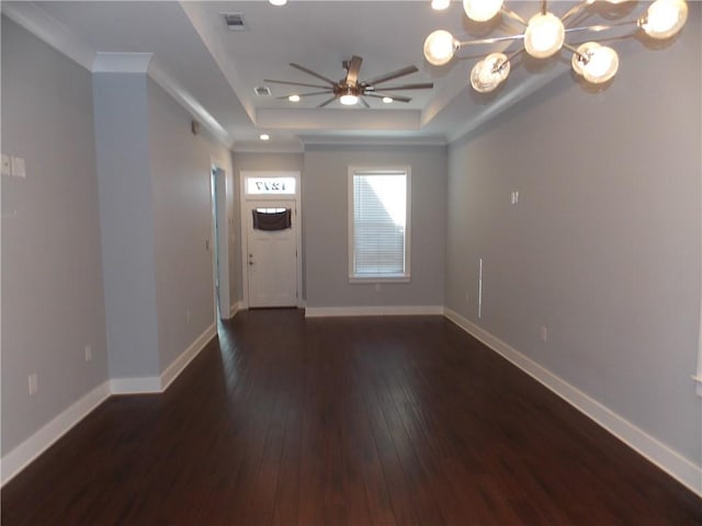 spare room with ceiling fan with notable chandelier, dark hardwood / wood-style floors, a raised ceiling, and crown molding