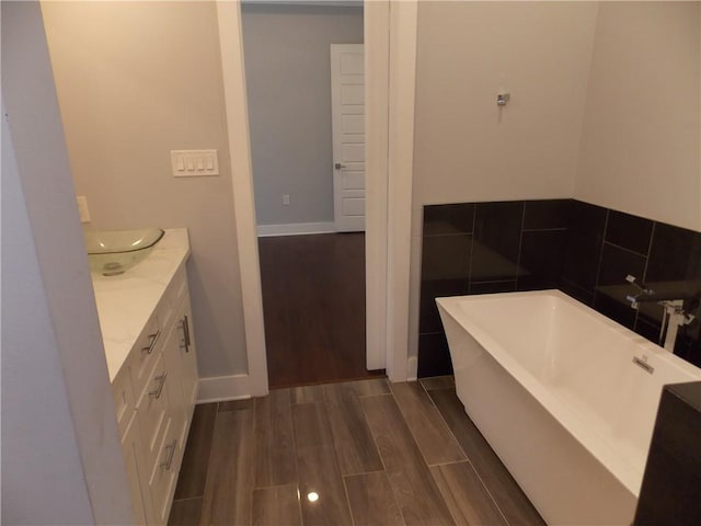 bathroom with a bathing tub, vanity, and wood-type flooring