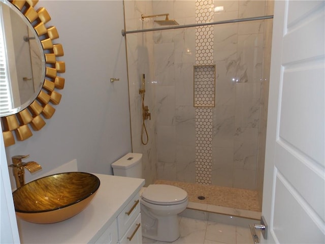 bathroom featuring tile floors, toilet, a tile shower, and vanity with extensive cabinet space