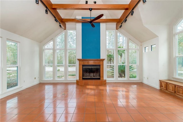 unfurnished living room with beam ceiling, light tile flooring, and track lighting