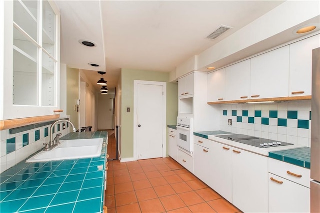 kitchen featuring white oven, light tile flooring, sink, white cabinets, and tile counters