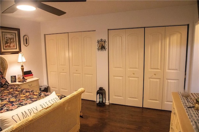 bedroom featuring ceiling fan, multiple closets, and dark hardwood / wood-style flooring