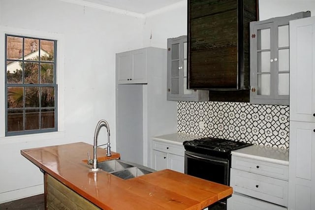 kitchen with backsplash, gas range, white cabinetry, and sink