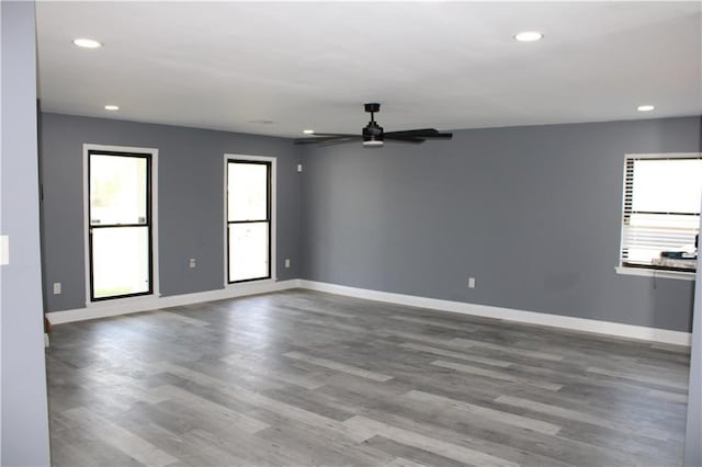 empty room with wood-type flooring, ceiling fan, and a healthy amount of sunlight