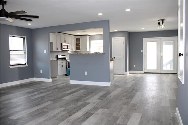 unfurnished living room featuring dark hardwood / wood-style flooring, ceiling fan, and french doors