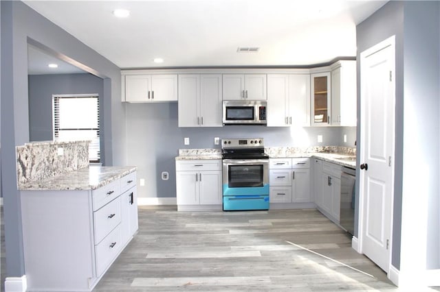 kitchen featuring sink, light stone counters, stainless steel appliances, and light hardwood / wood-style flooring