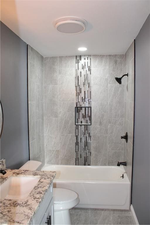 full bathroom featuring vanity, tiled shower / bath combo, and toilet