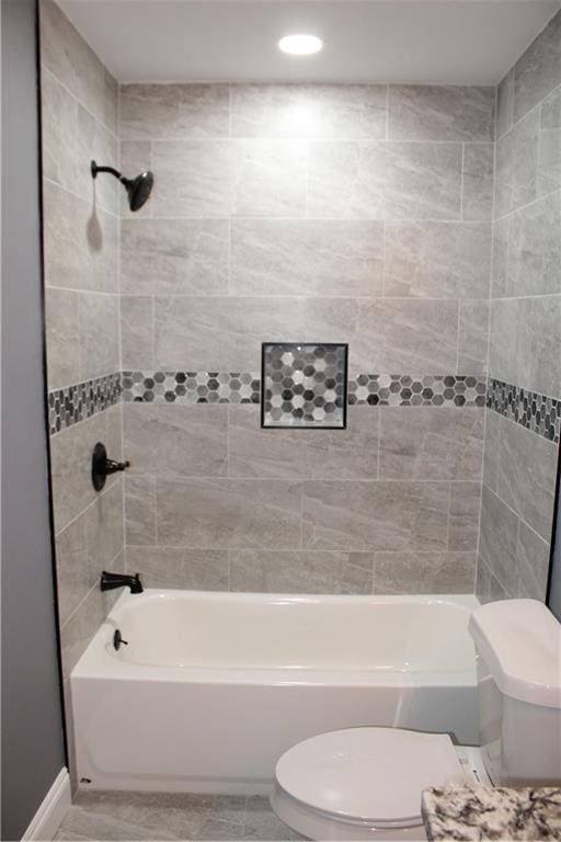 bathroom with tiled shower / bath combo and toilet