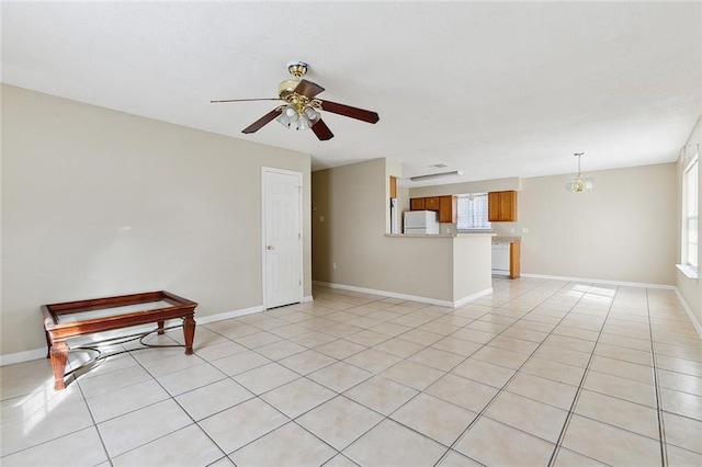 unfurnished room featuring light tile patterned flooring and ceiling fan with notable chandelier