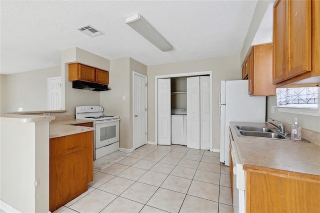 kitchen with sink, a textured ceiling, light tile patterned floors, kitchen peninsula, and white appliances