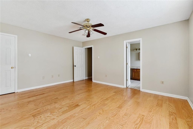 unfurnished bedroom featuring ceiling fan, light hardwood / wood-style flooring, a textured ceiling, and ensuite bathroom