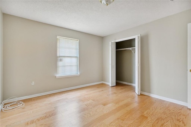 unfurnished bedroom featuring a textured ceiling, light hardwood / wood-style floors, and a closet