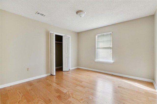 unfurnished bedroom featuring light hardwood / wood-style floors, a closet, and a textured ceiling