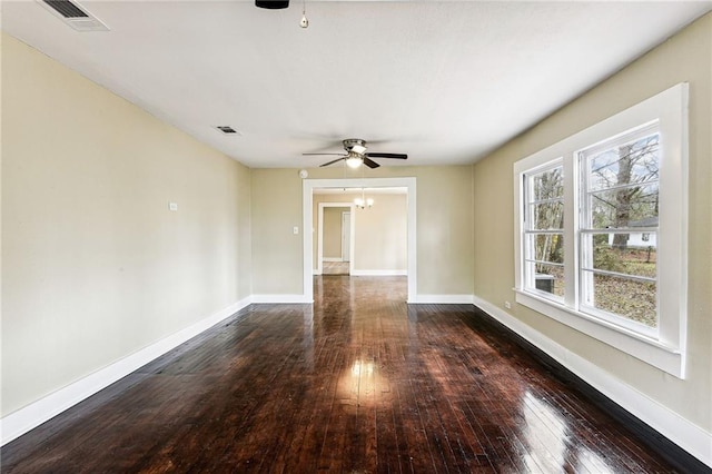 spare room with ceiling fan with notable chandelier and dark hardwood / wood-style flooring