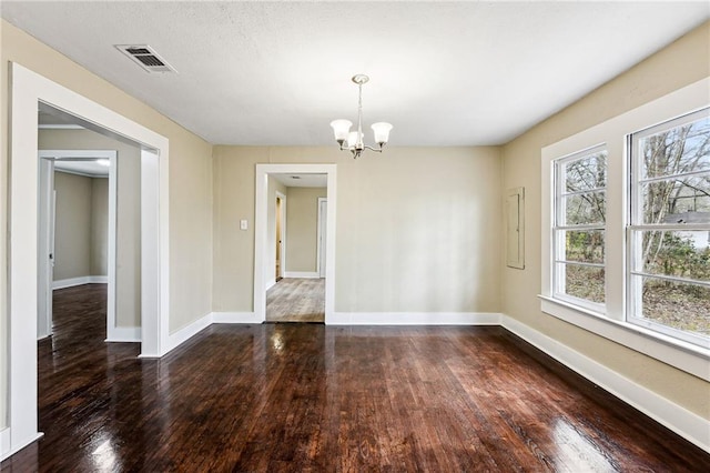 spare room with dark hardwood / wood-style flooring and an inviting chandelier