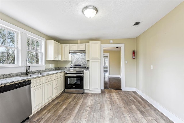 kitchen featuring light stone countertops, sink, backsplash, hardwood / wood-style floors, and appliances with stainless steel finishes