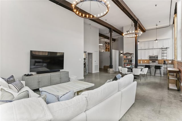 living room with concrete floors, beamed ceiling, a towering ceiling, and a chandelier