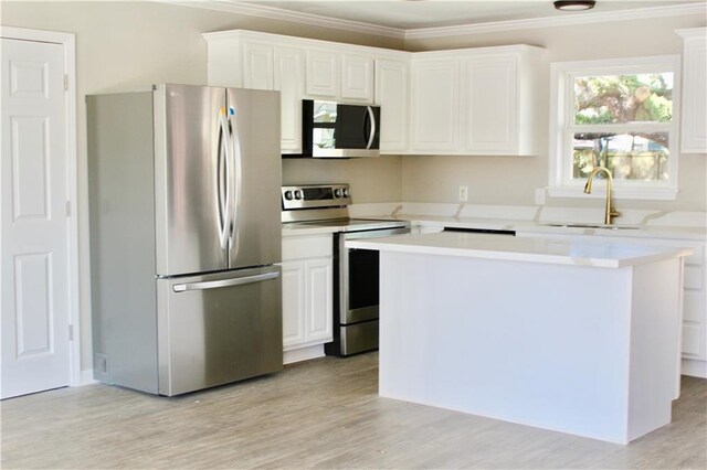 kitchen with white cabinetry, ornamental molding, stainless steel appliances, and light wood-type flooring