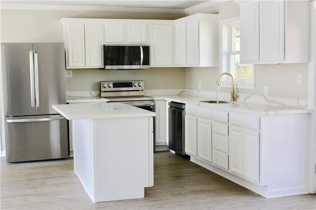 kitchen with ornamental molding, a kitchen island, stainless steel appliances, and light hardwood / wood-style floors