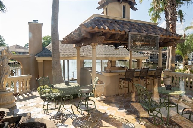 view of patio / terrace with a bar, ceiling fan, exterior kitchen, and a pergola