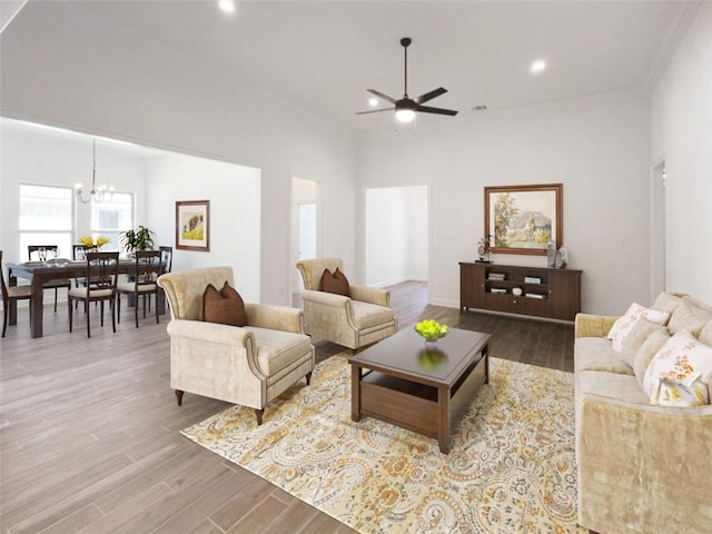 living room with ceiling fan with notable chandelier and hardwood / wood-style flooring