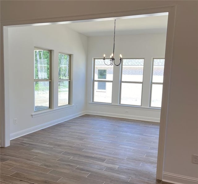 unfurnished dining area with wood-type flooring and a chandelier