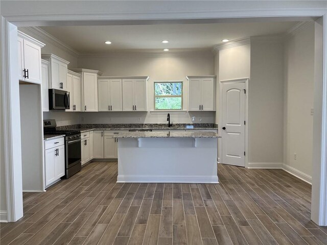 kitchen featuring white cabinets, appliances with stainless steel finishes, dark wood-type flooring, and a center island