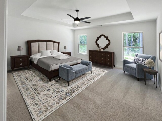 carpeted bedroom featuring ceiling fan, a raised ceiling, and multiple windows