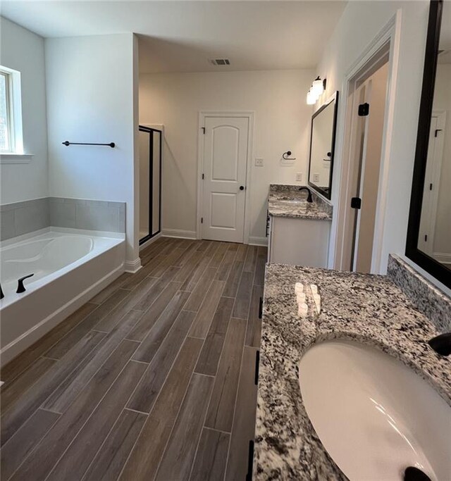 bathroom with wood-type flooring, vanity, and separate shower and tub