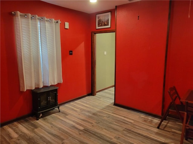 spare room with a wood stove and hardwood / wood-style flooring