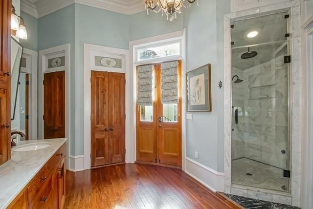 bathroom featuring walk in shower, vanity, hardwood / wood-style flooring, a notable chandelier, and ornamental molding