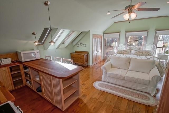 interior space with hardwood / wood-style floors, lofted ceiling with skylight, and ceiling fan