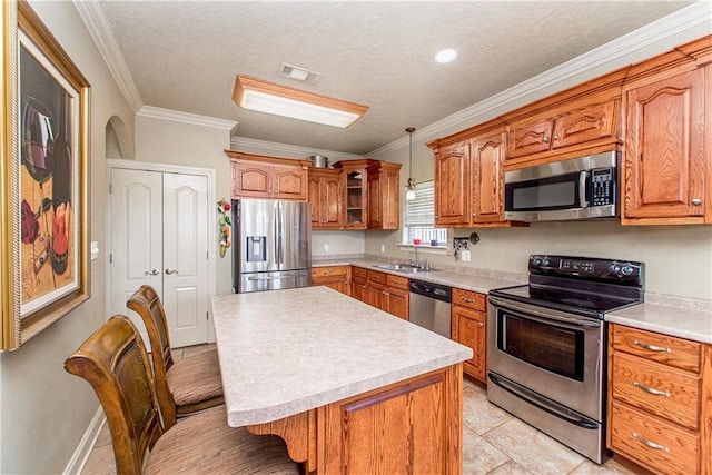 kitchen with stainless steel appliances, a kitchen island, light tile flooring, a breakfast bar, and crown molding