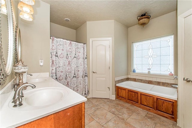 bathroom featuring a textured ceiling, tile flooring, a bathtub, and double vanity